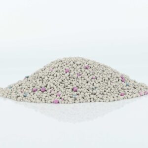 Pile of regular dust-free bentonite cat litter showcasing its uniform granule texture with pink and blue odor control beads.