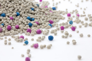 Colorful bentonite cat litter granules with blue and purple accents, showcasing its clumping and odor control properties.